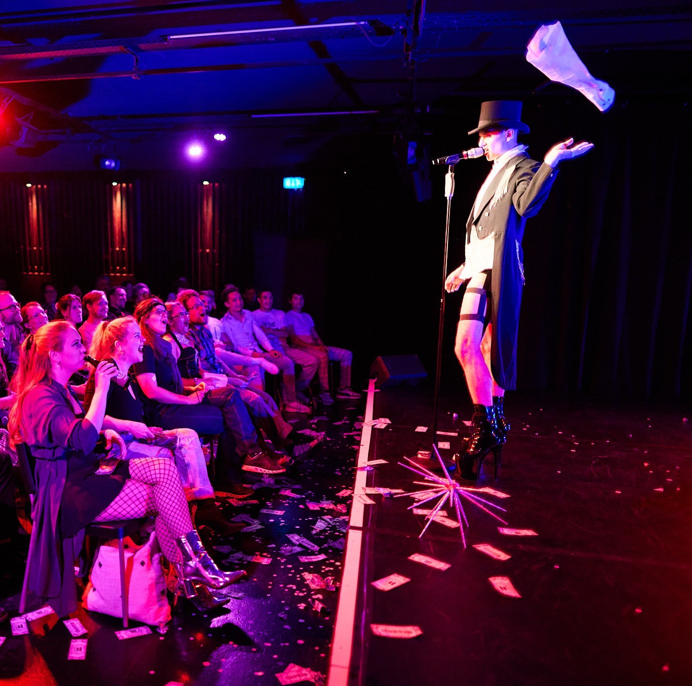 Roylesque is seen performing to a crowd. A white shirt sleeve flies in the air as they throw it away.